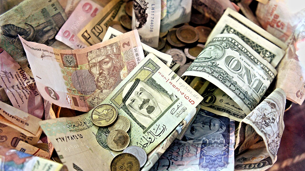 Person checking their phone to receive money, with peso bills on the table